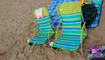 Reviewer's blue and green striped beach chairs lined up on the sand