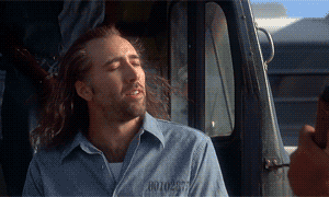gif of nicholas cage in the movie &quot;con air&quot; smiling as he feels the breeze on his face