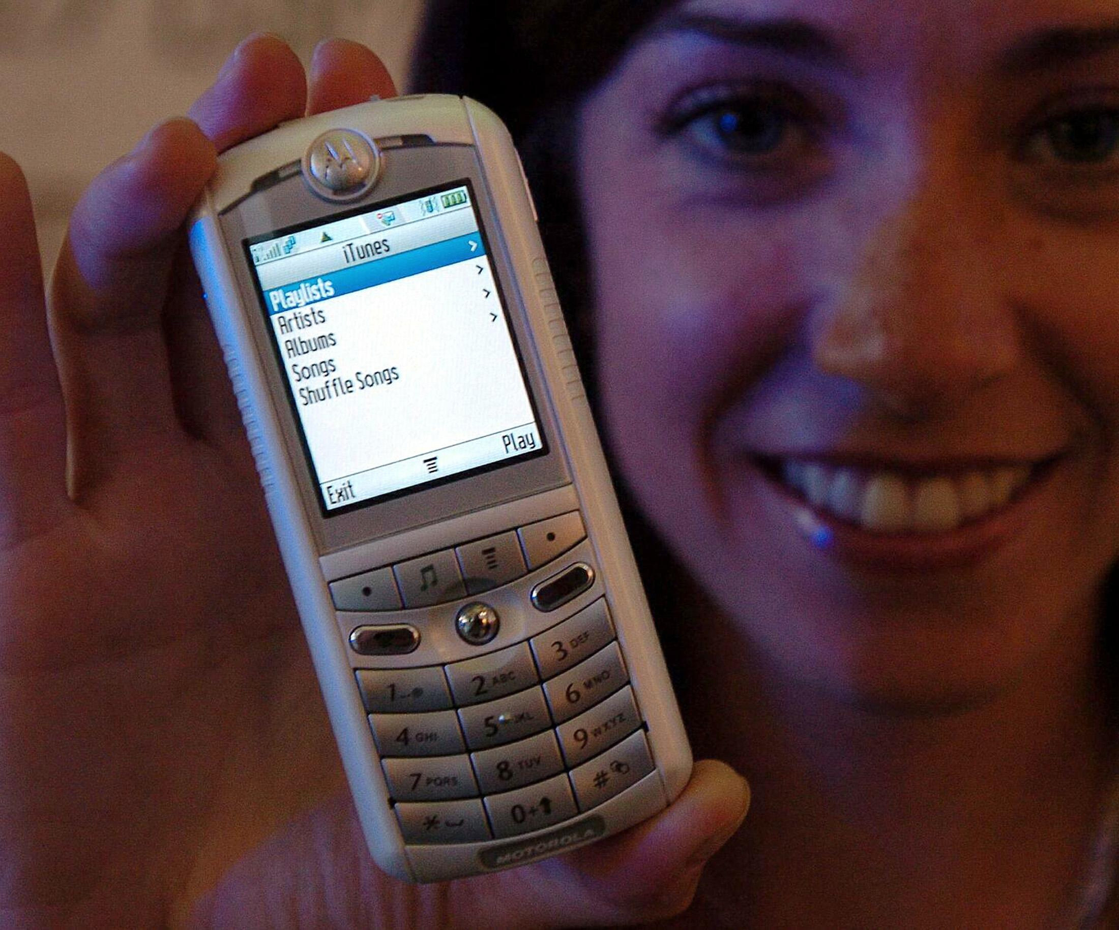 Girl holding a Motorola phone with iTunes on home screen on it. 