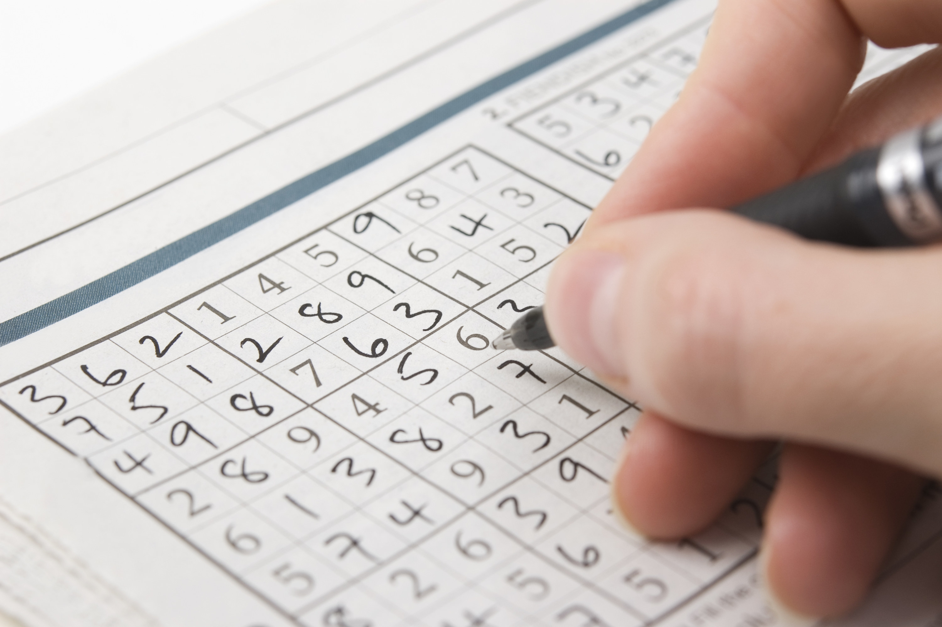 A stock image of a person doing a Sudoku puzzle. 