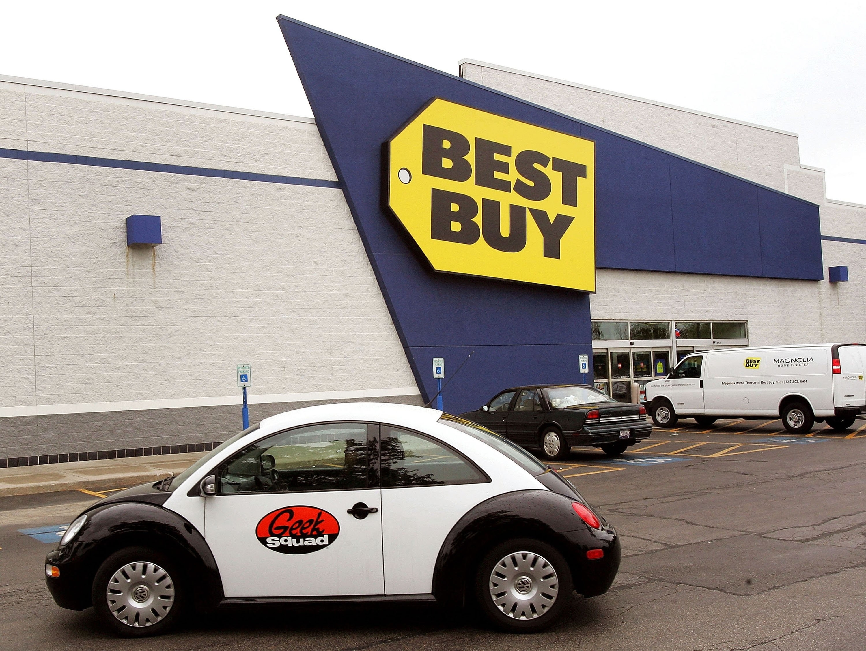 A black and white Geek Squad Volkswagen Beetle parked outside a Best Buy.