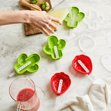 Hand pouring liquid into cactus and strawberry popsicle molds 