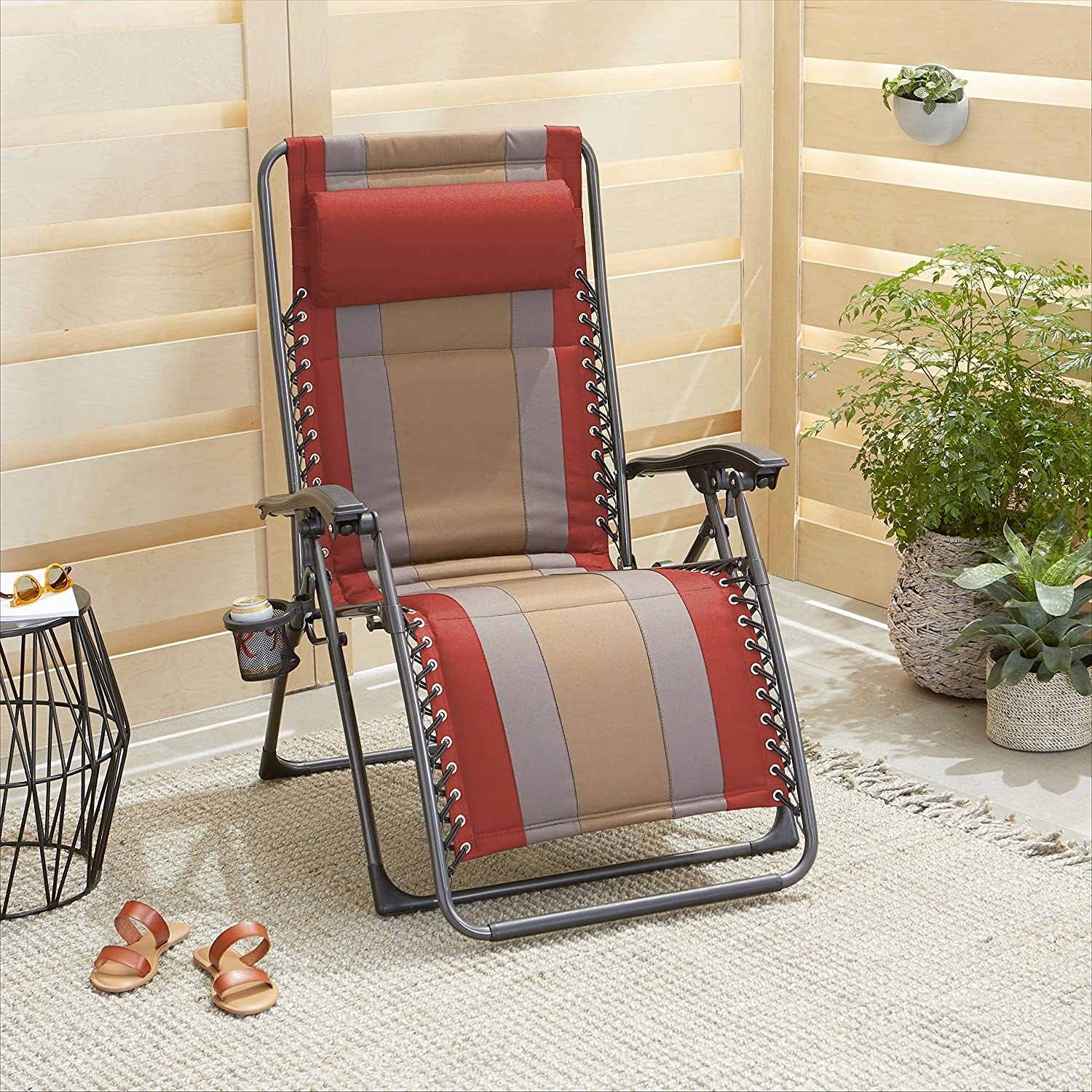 A black metal framed beach chair with red, gray, and tan cushion