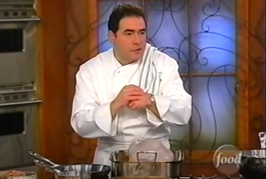 A screengrab of Emeril Lagasse standing behind a stove on the set of Emeril Live. 