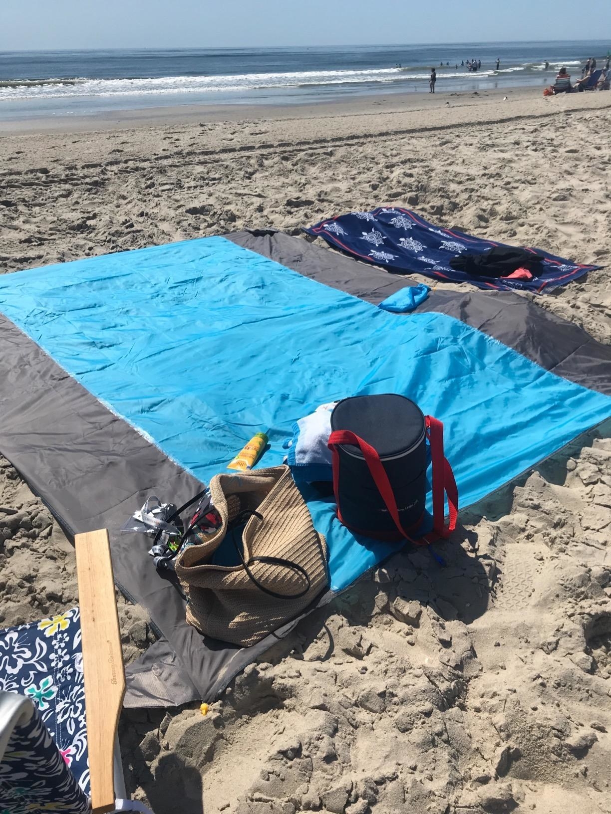 A gray and light blue beach blanket laid out on the beach