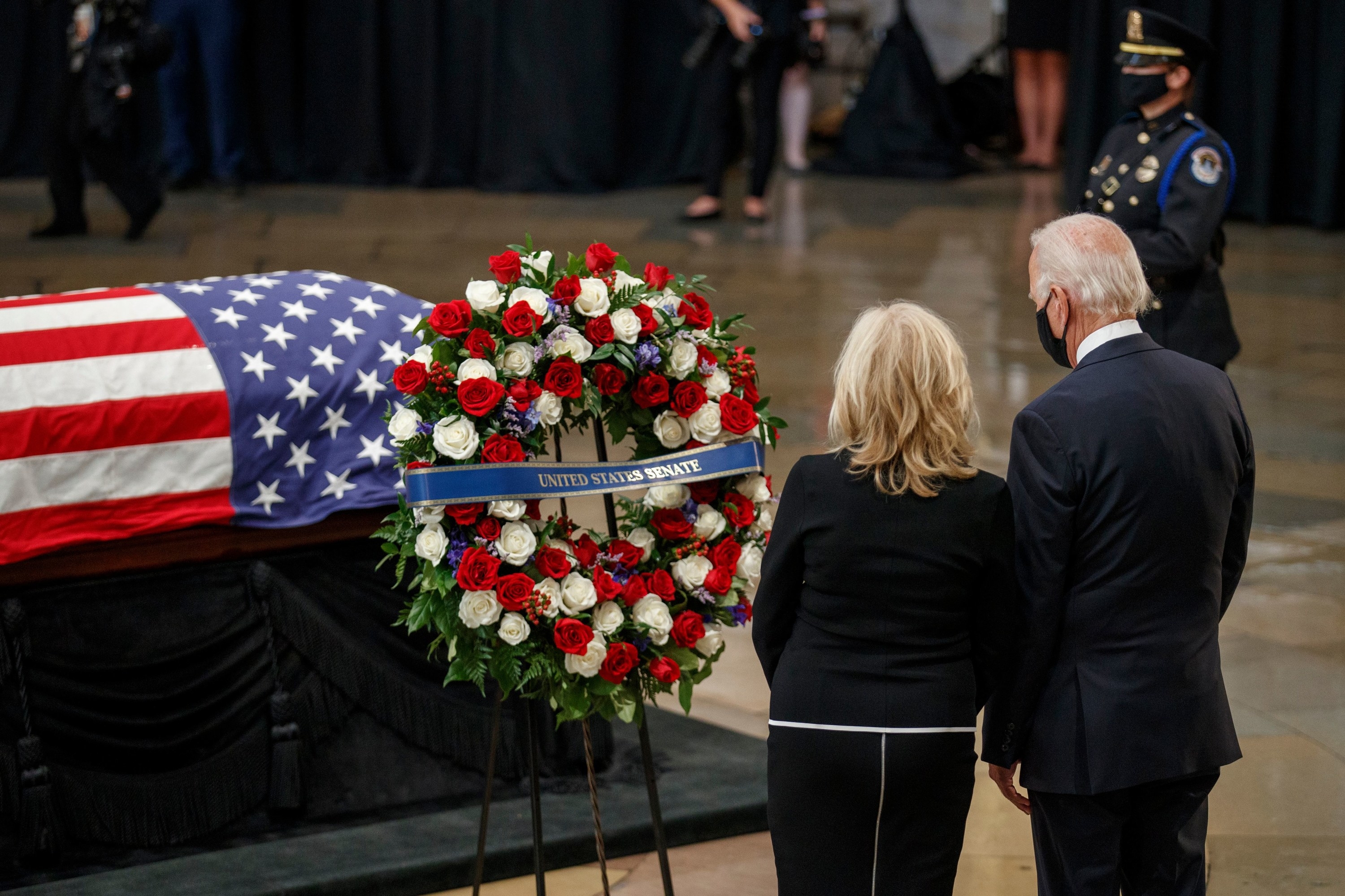 Joe and Jill Biden stand by the flag-draped casket; a wreath of roses has a sash that reads &quot;United States Senate&quot;