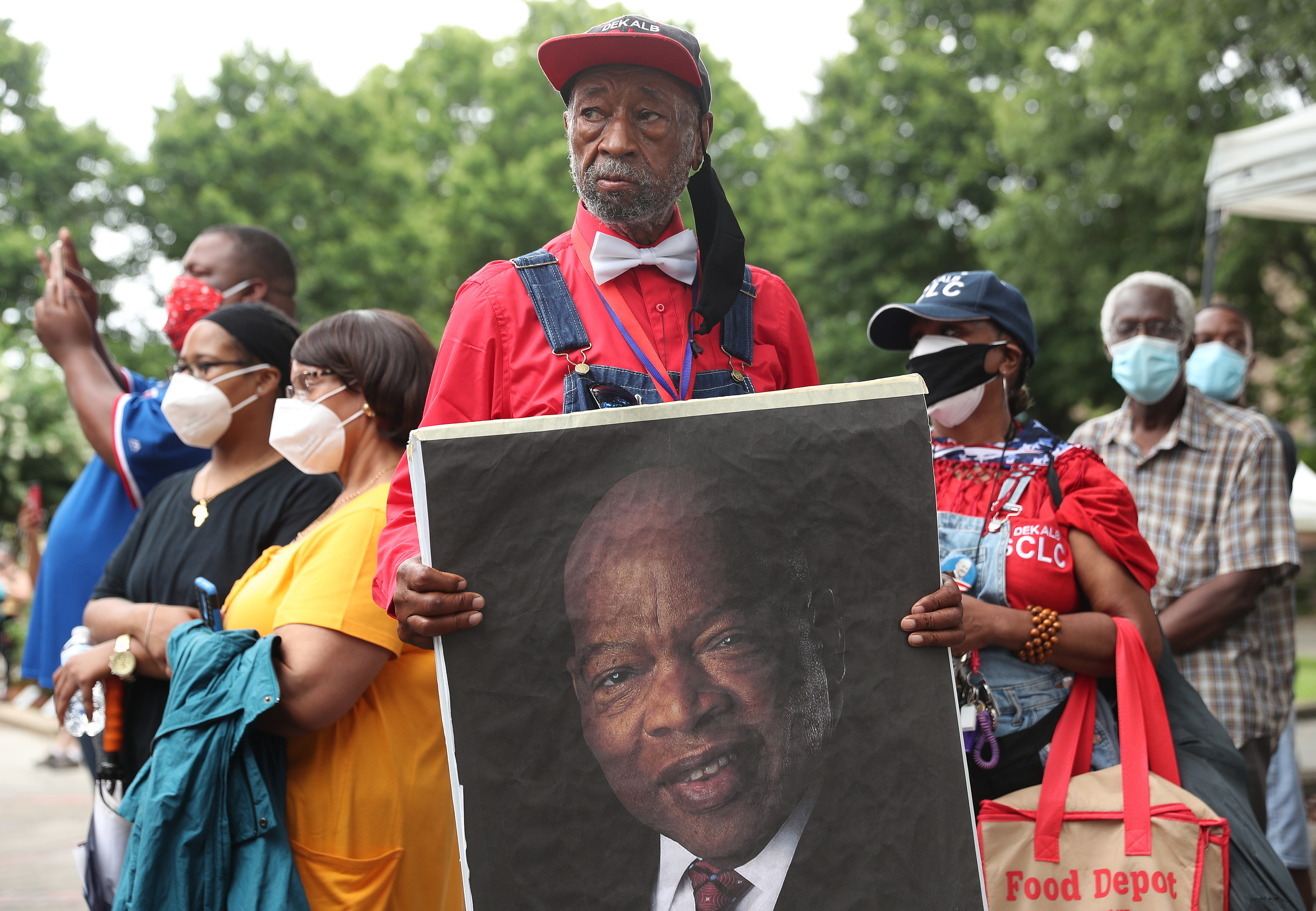 A man holds up a large image of John Lewis