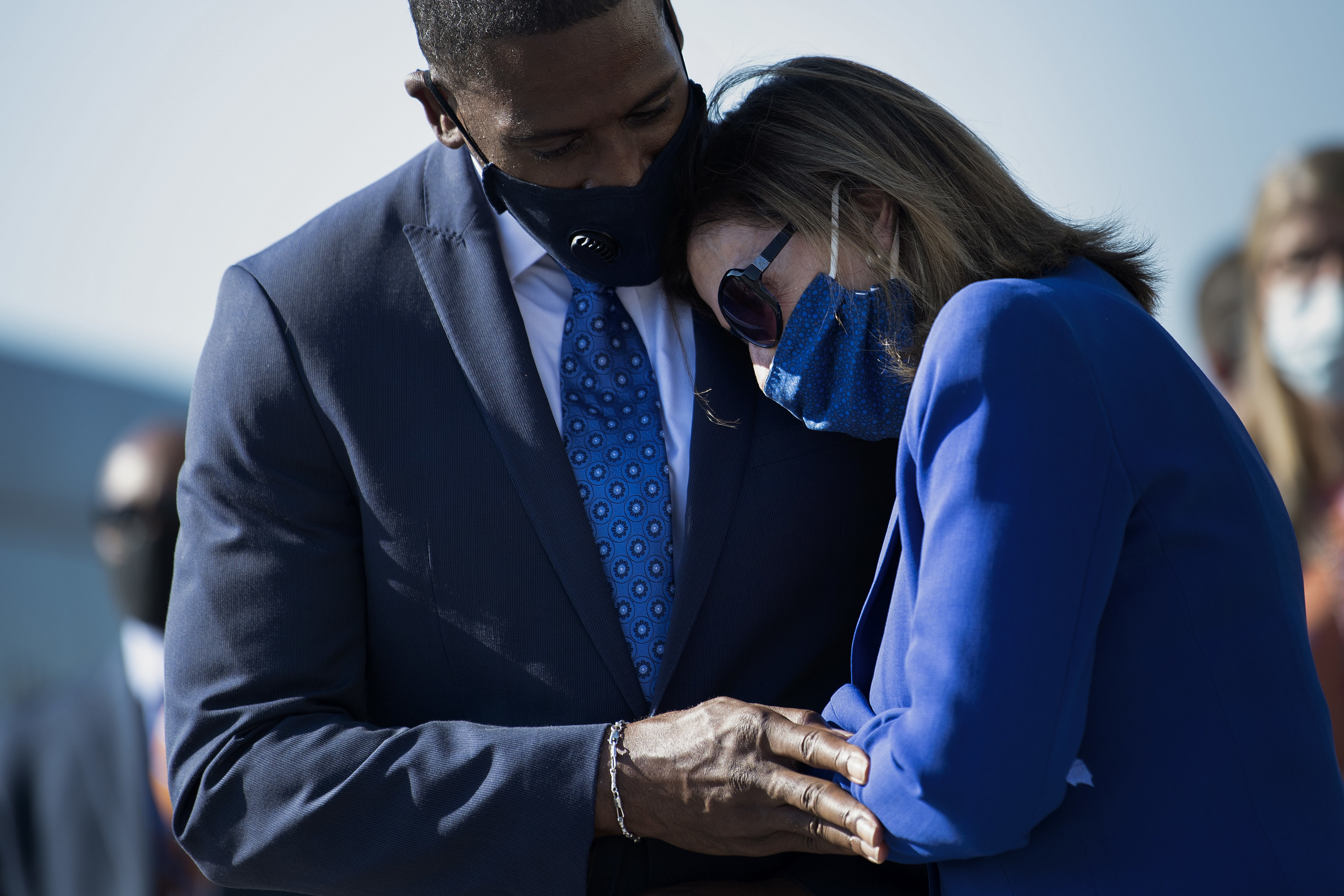 Nancy Pelosi leans onto the shoulder of Michael Collins; both wear masks