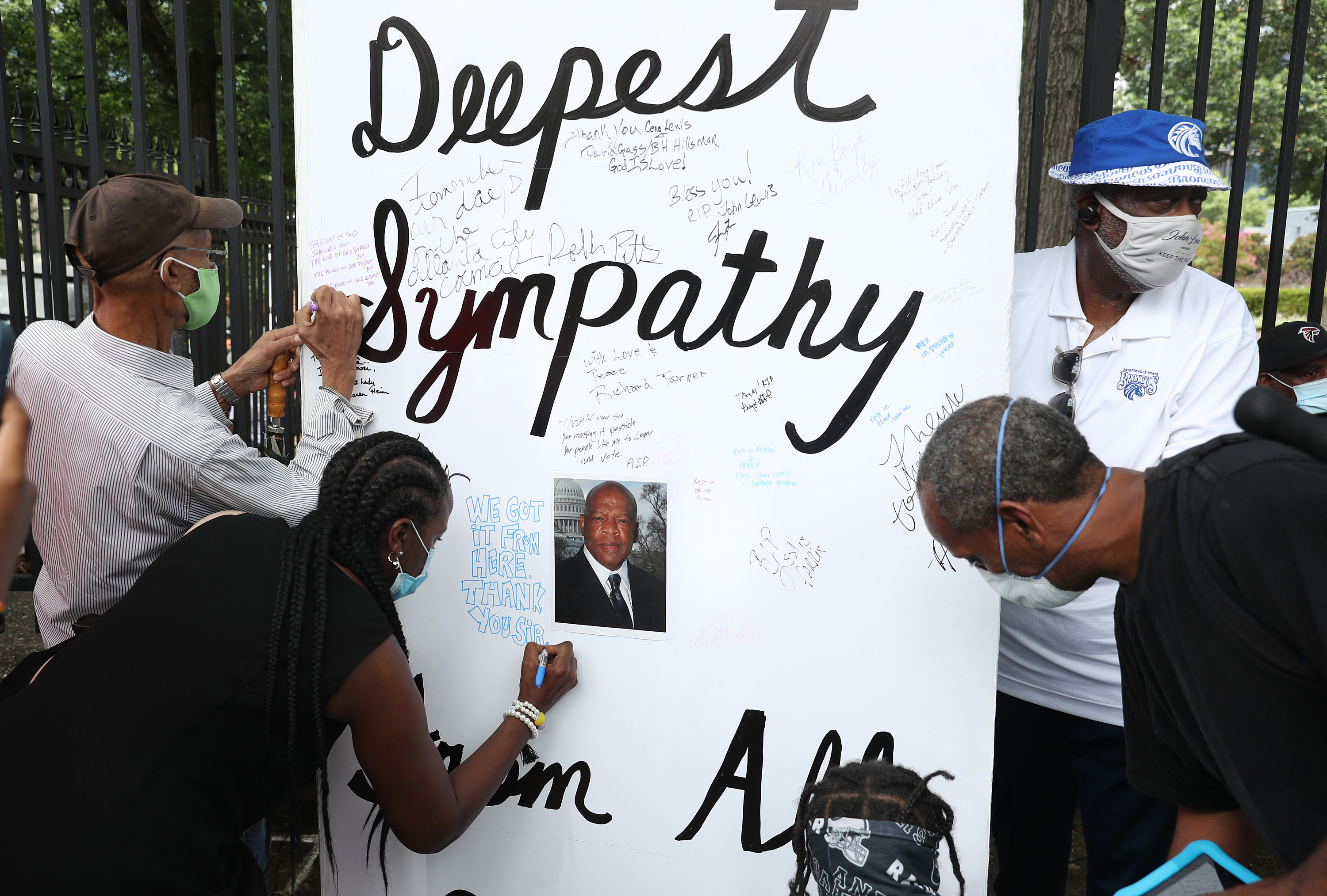 A large poster board for John Lewis reads &quot;Deepest Sympathy&quot; as people use markers to write notes