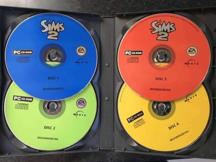 A open case for the Sims 2 containing four CD-roms. 