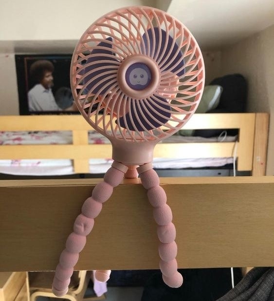 Reviewer&#x27;s picture of the portable fan attached to their bed post