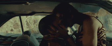 Queen and Slim kissing passionately in their car. 