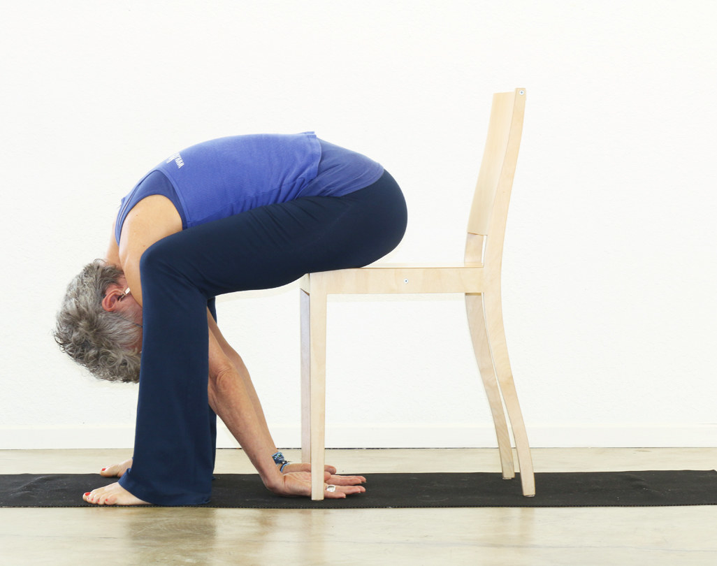 A woman bends over in the yoga pose described below. 