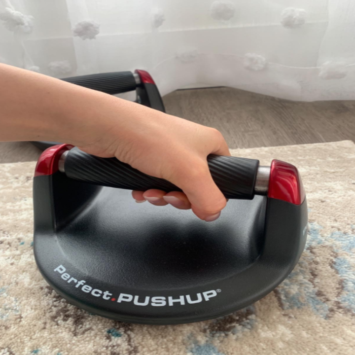 A hand grips the push up bar mounted on a base plate