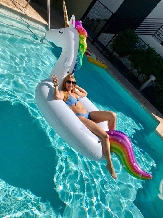 A reviewer sitting back on the unicorn float in a pool
