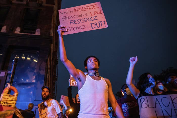 A young man holds a protest sign as he and protesters march in Omaha in early June