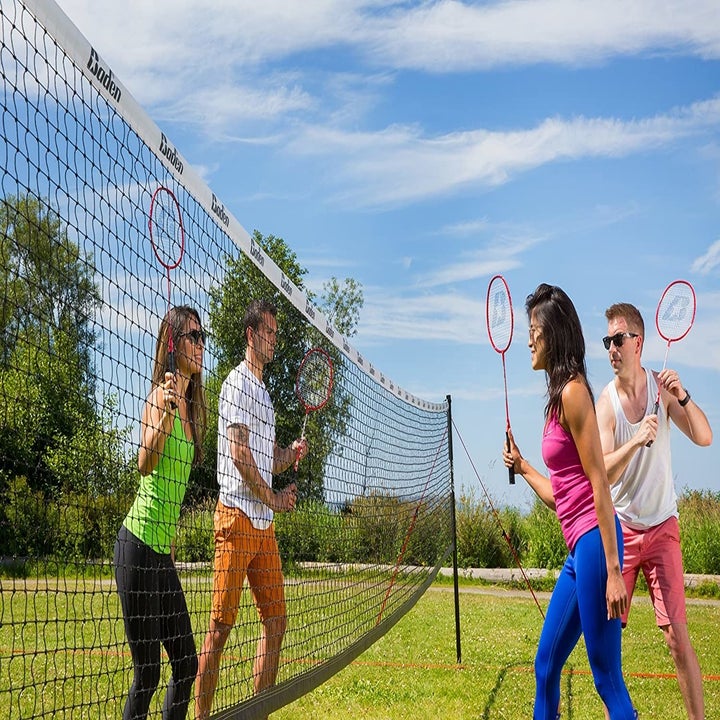 Four models playing badminton in teams of two on either side of a black net with white piping