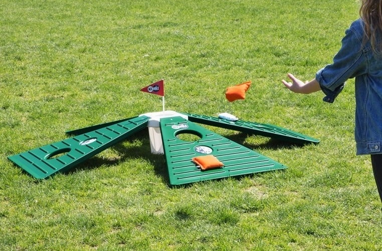 A person tossing a bean bag on the cornhole golf game