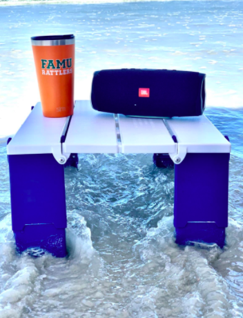 Reviewer places white and blue beach table with a speaker and drink near waves 
