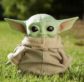 the baby yoda doll in a tan coat outfit