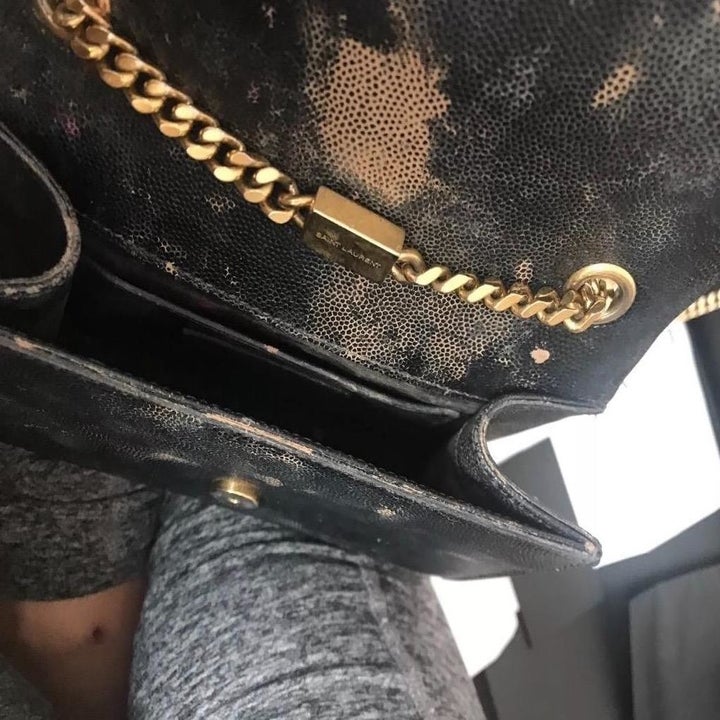 Reviewer's before photo of a black leather purse with stains all over it 