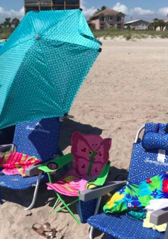 Reviewer places blue-patterned clamp umbrella over blue beach chair