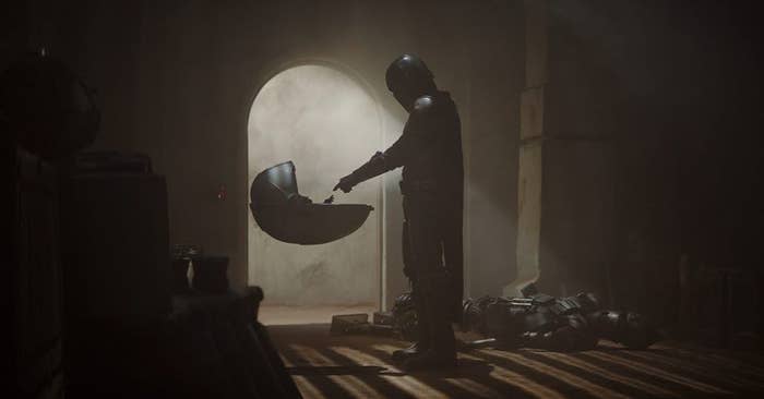 the mandalorian holding his finger out to baby yoda in his pod carriage