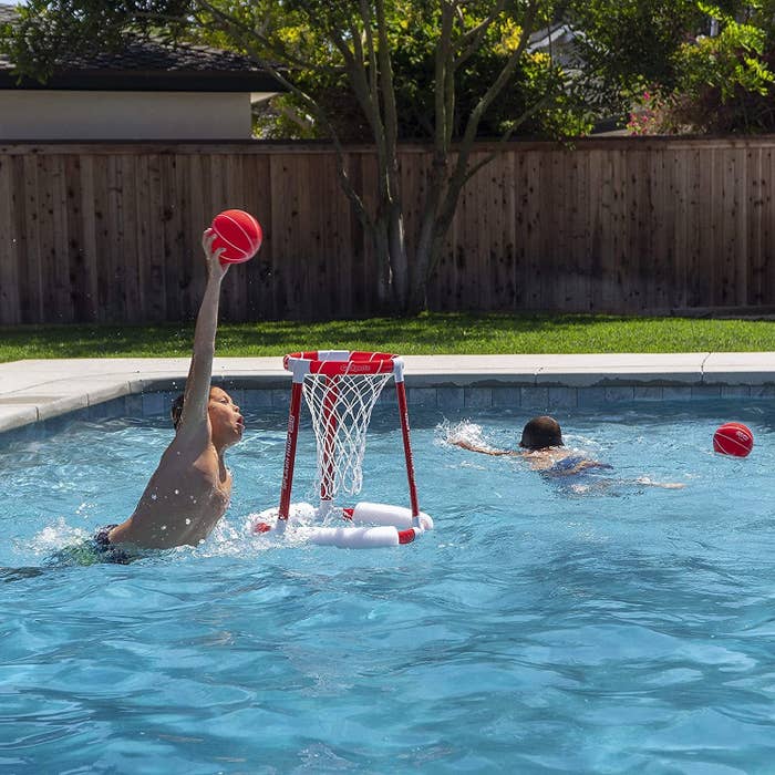 A model about to dunk a ball into the floating hoop in the pool