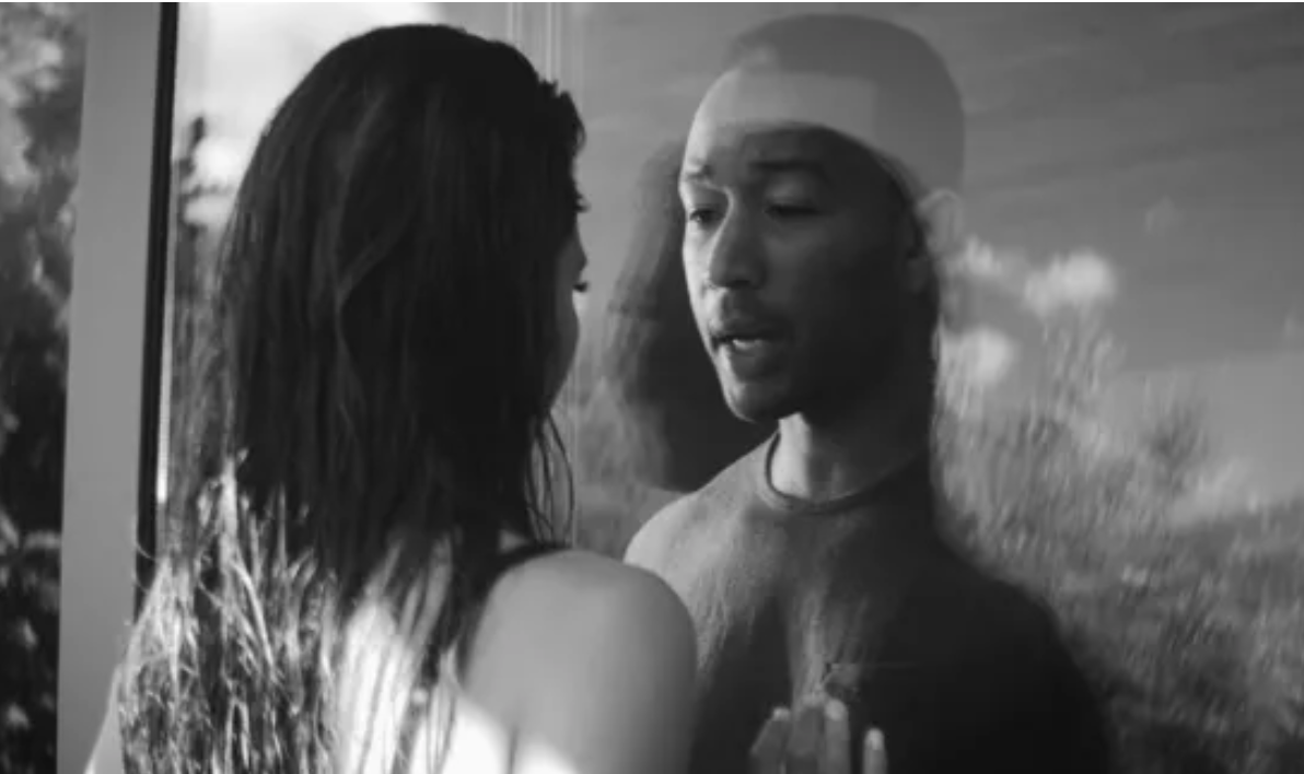 John Legend and Chrissy Teigen lock eyes all romantic-like though a glass door