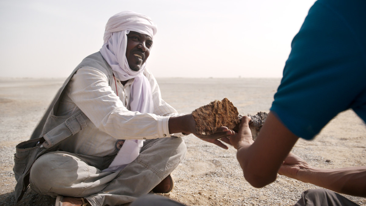 A man hands another a rock