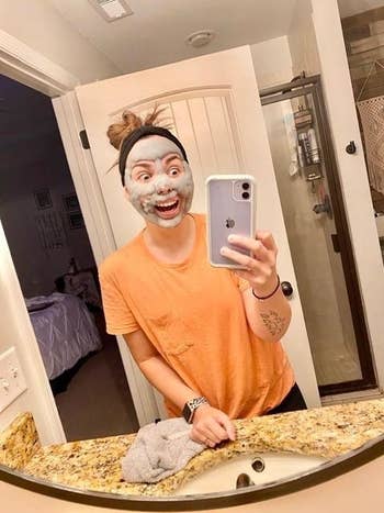 reviewer looks elated to have grey cloud-like face mask on 