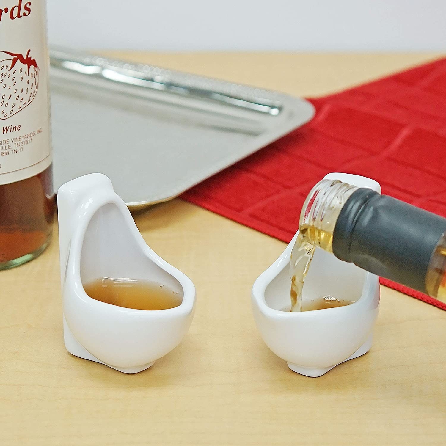 Shot glasses shaped like urinals with liquid in them that looks like urine