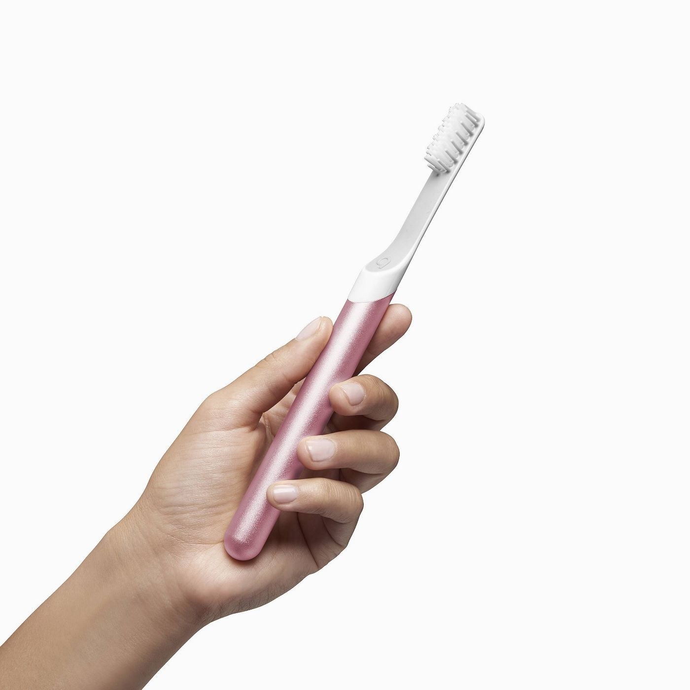 a model holding a sleek metallic pink toothbrush