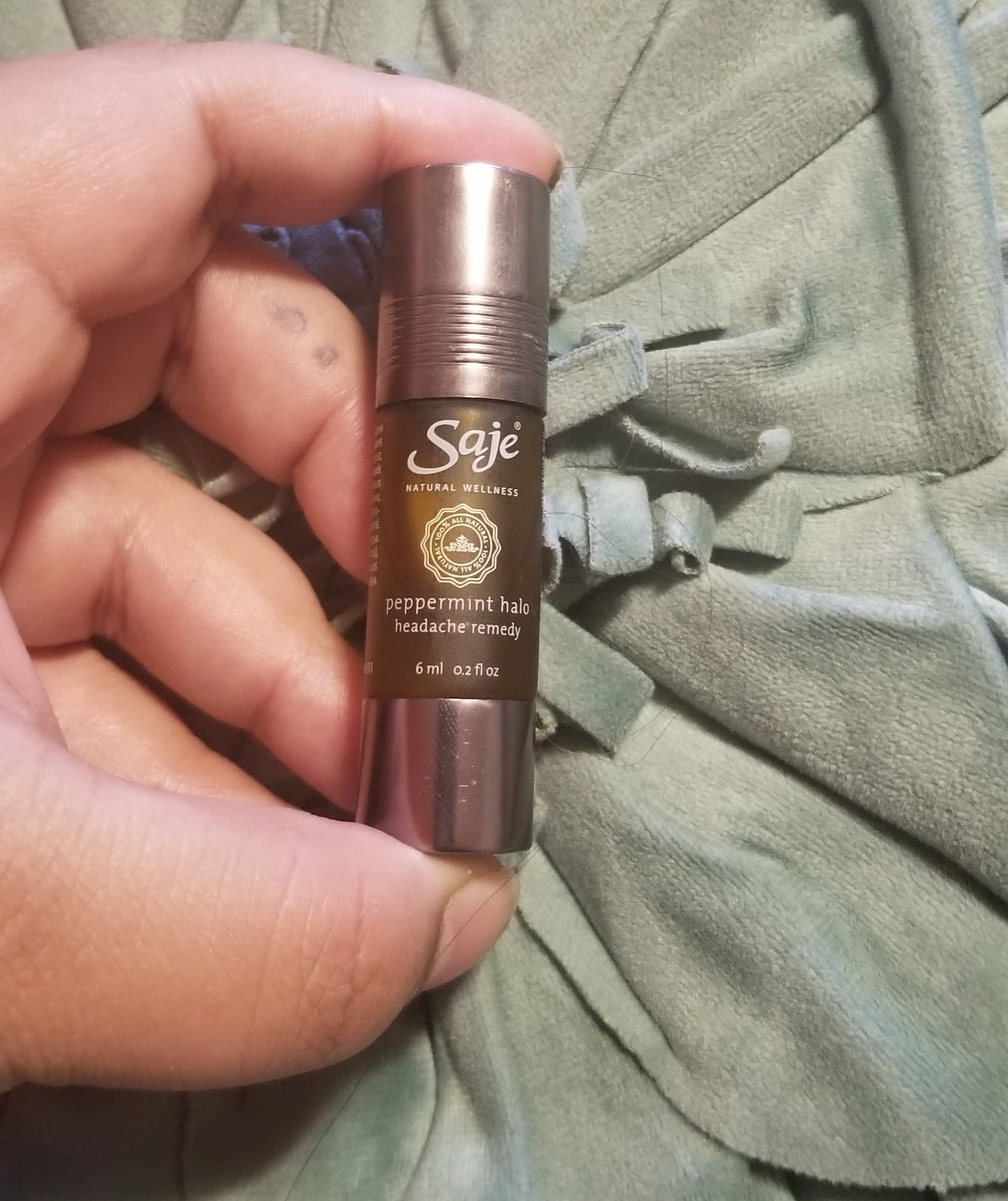 A hand holding a tube of Peppermint Halo Headache Remedy