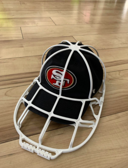 A reviewer photo of the white plastic cage, which is shaped like an oversized baseball cap, with a cap inside