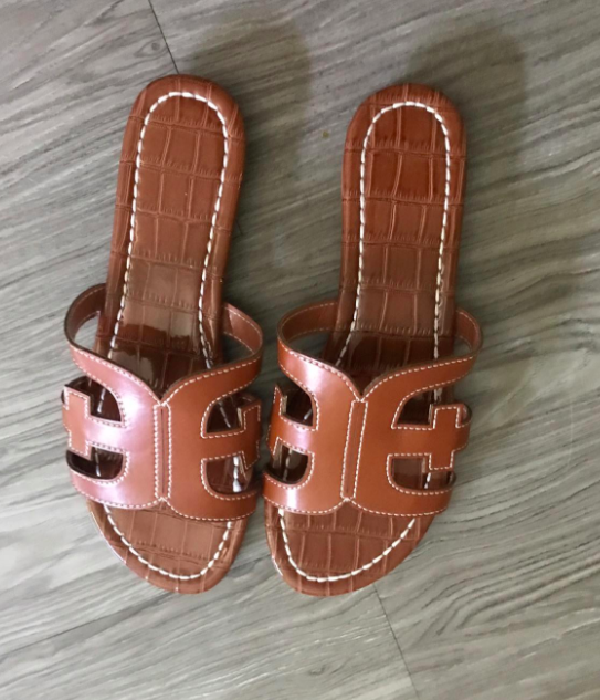 A customer review photo of the faux-leather slides in brown.