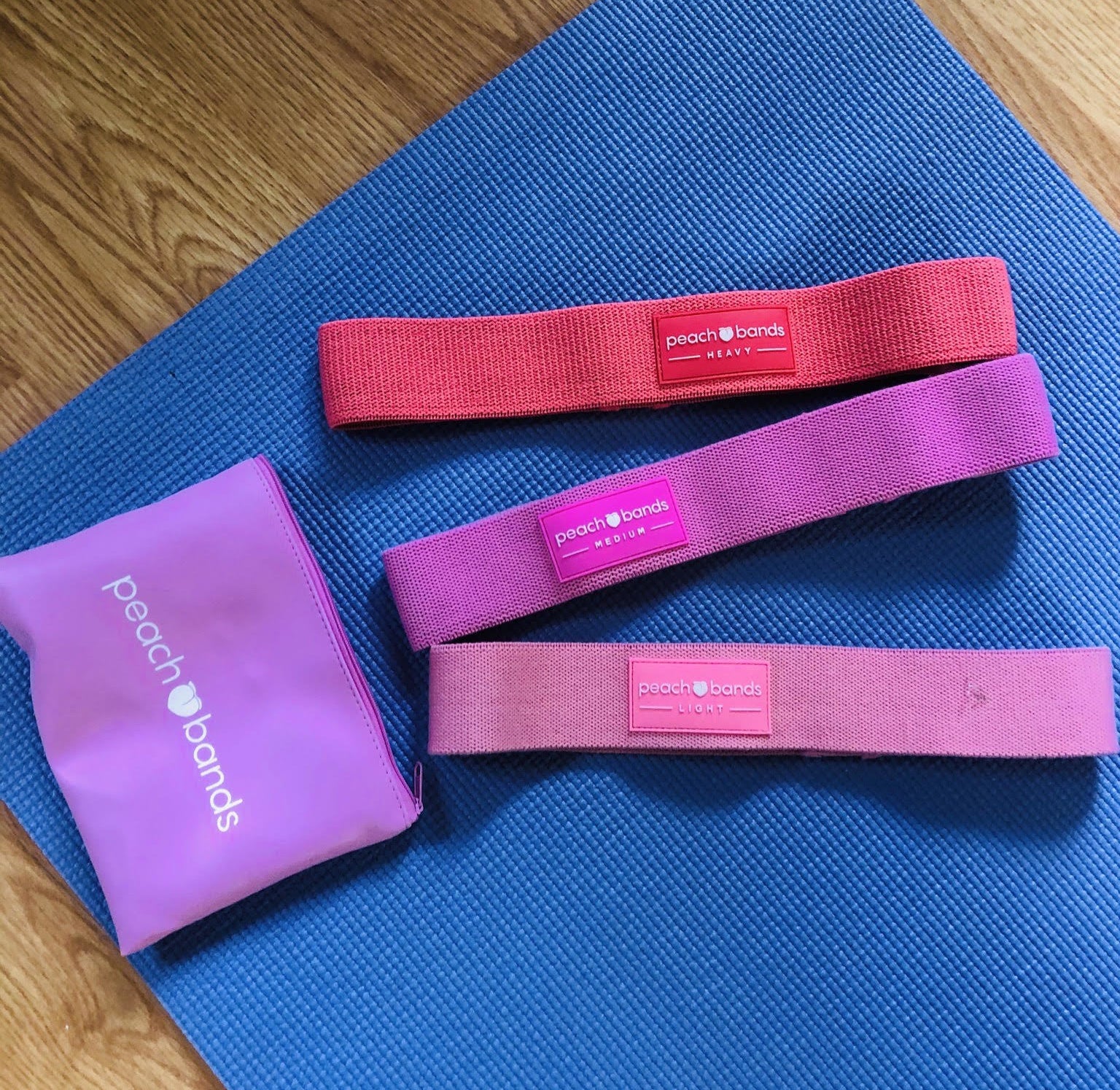 The set of three peach bands lying on a workout mat