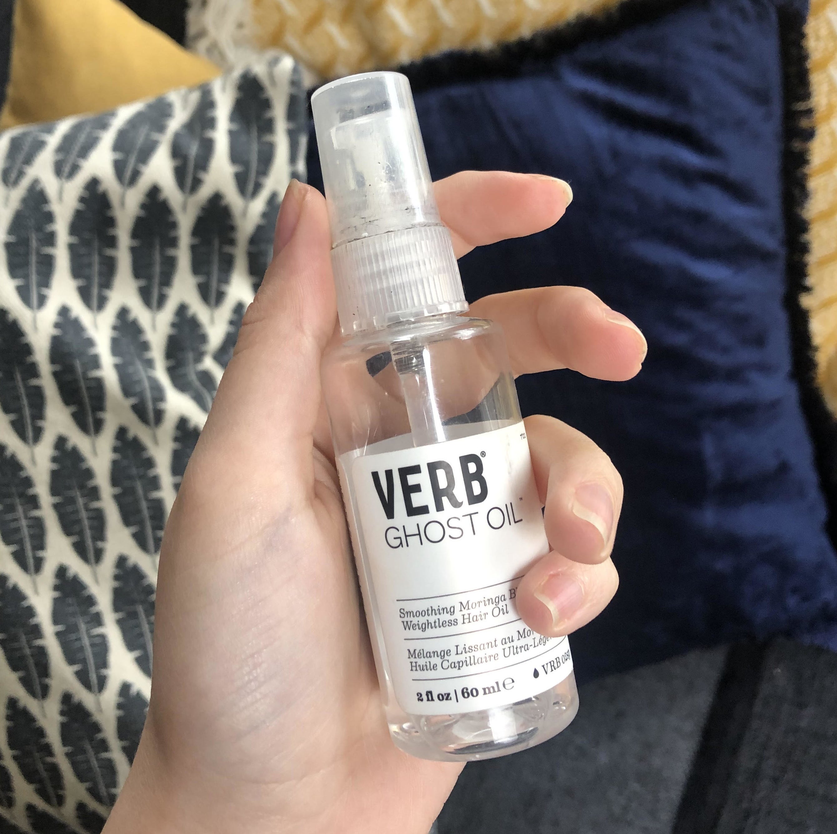 hand holding clear bottle with white spray nozzle