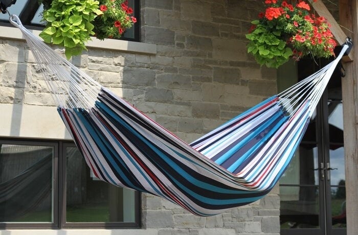 Striped blue and red camping hammock outside of home