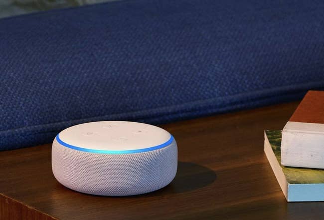 A white circular Amazon Echo dot on a table 