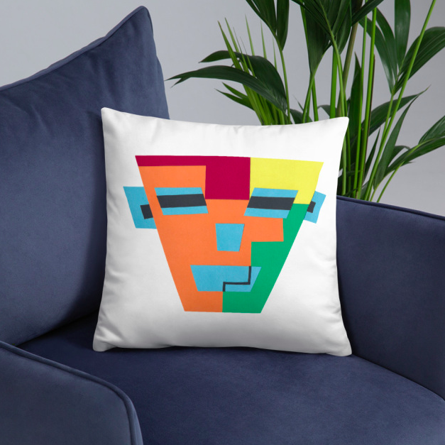 An accent pillow with a colorful-printed face on a dark blue arm chair