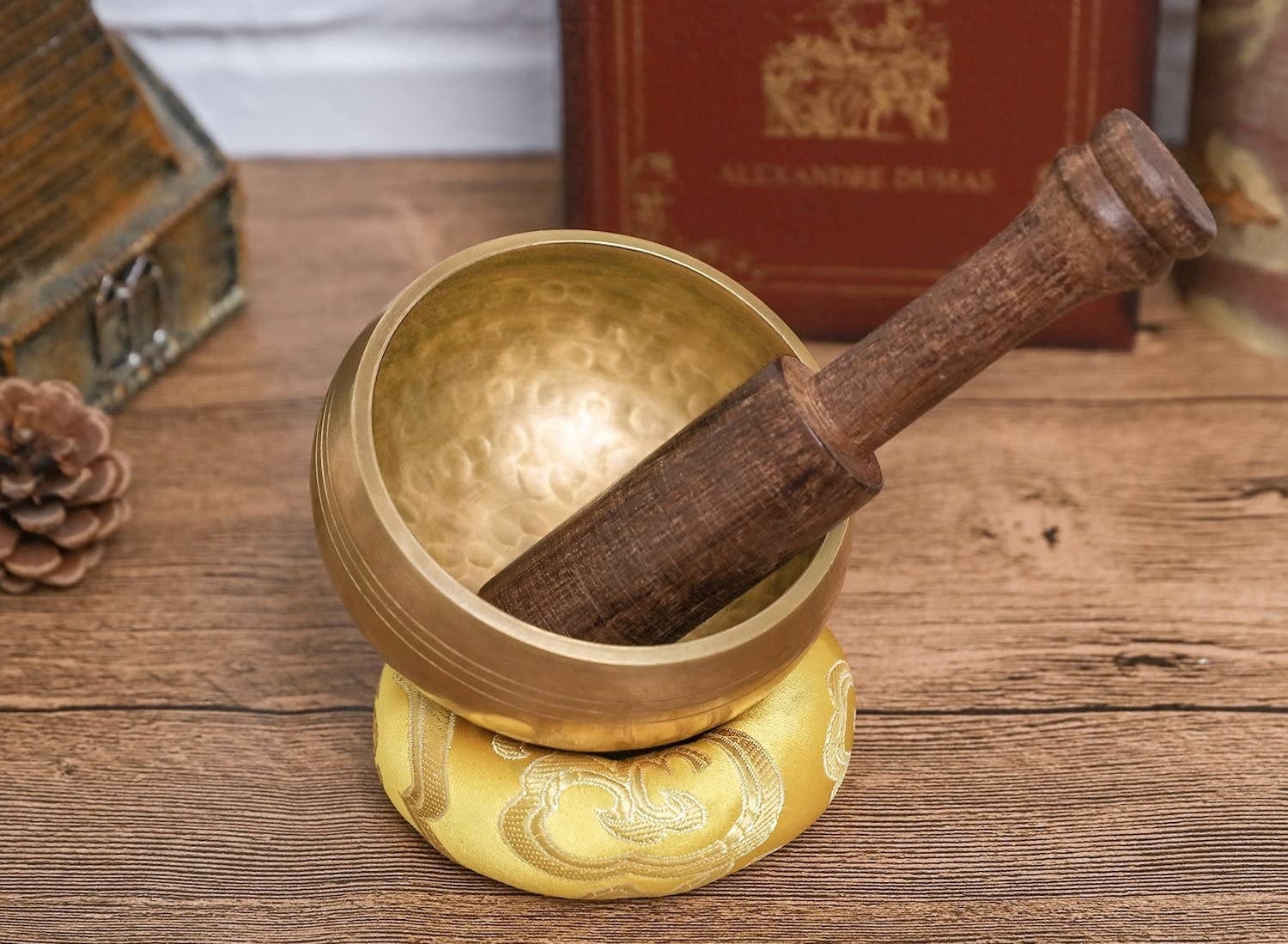 A singing bowl with a wooden striker in it on a cushion on a table