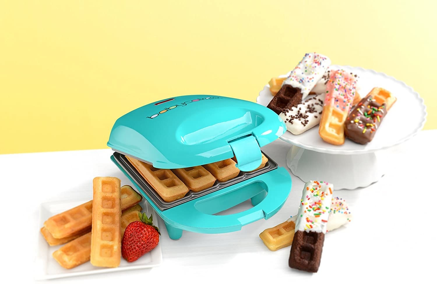 A waffle stick maker with waffle sticks on a plate some of which have been dipped in chocolate and have sprinkles