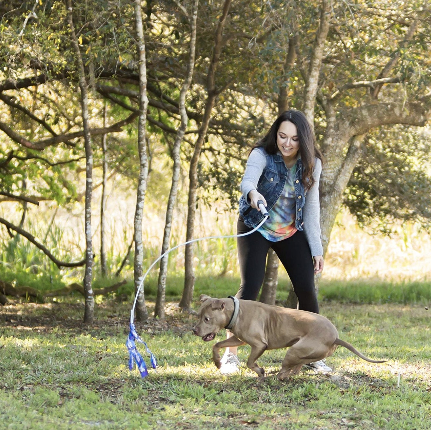 model holding the pole rope with their dog chasing after it