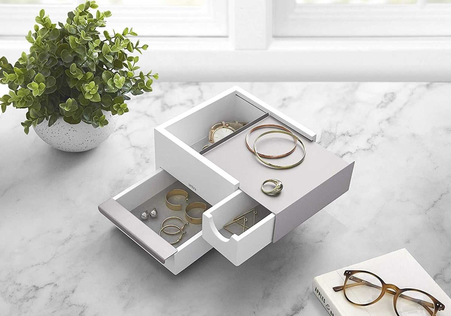 A small square jewelry box with multiple drawers of different sizes