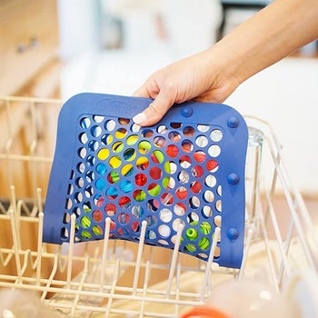 A hand putting the pouch with holes, closed vertically, in a dishwasher