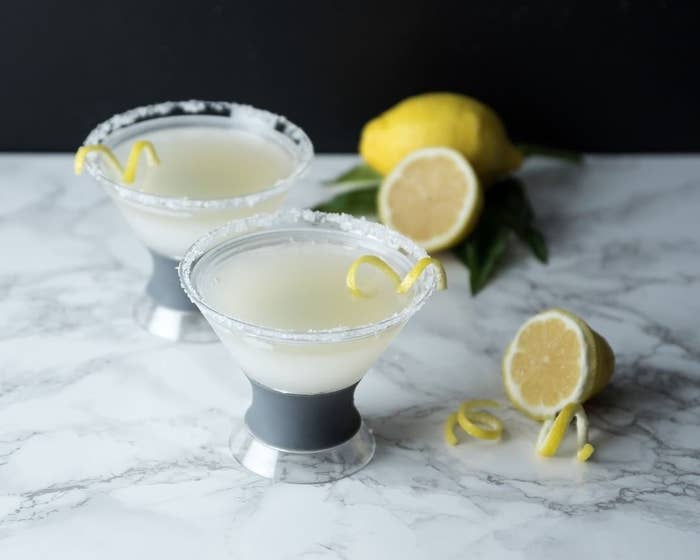 A pair of chilled martini glasses filled with margaritas on a marble countertop