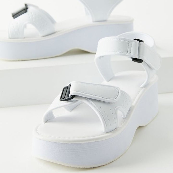 The sandals in white with two hook and loop straps made adjustable with black buckles 