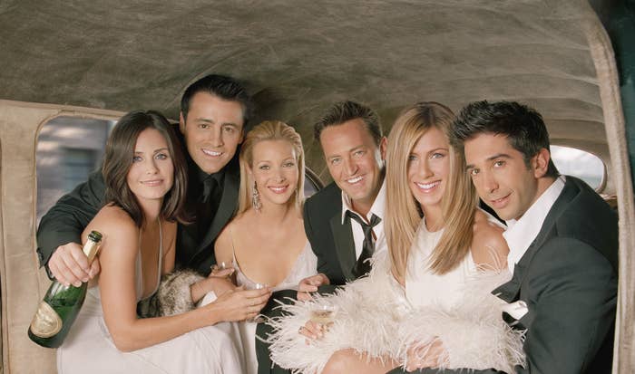 The cast of Friends dressed fancily in the back of a vintage car