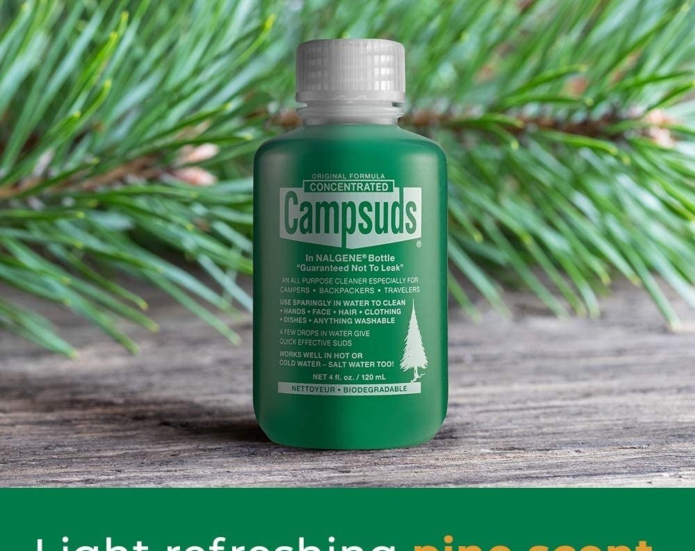 A bottle of Campsuds on a table in front of a spruce branch